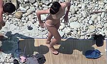Une beauté brune topless montre son corps sur une plage